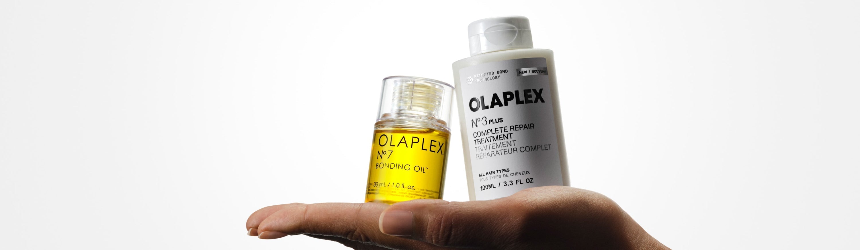 OLAPLEX Nº.3PLUS and Nº.7 Bonding Oil being held in the palm of an outstretched hand 