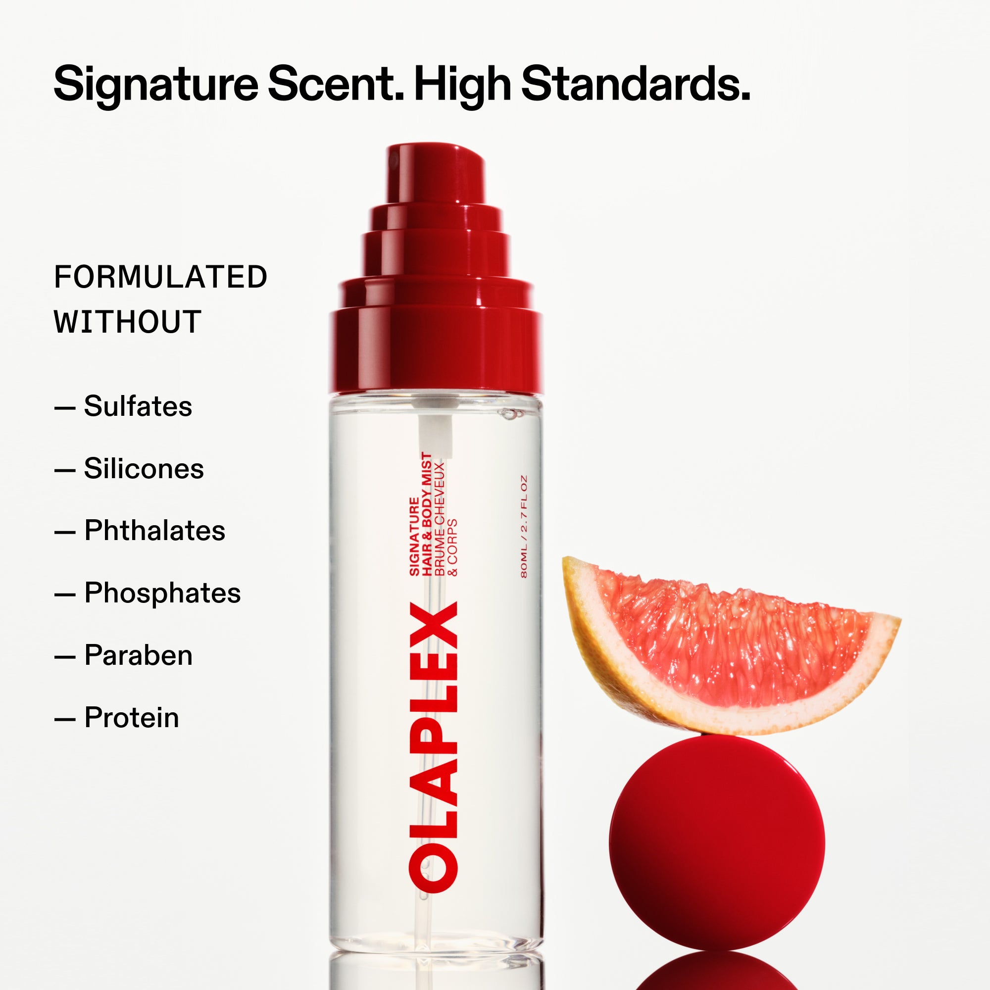 Un flacon de brume pour cheveux et corps OLAPLEX est posé à côté d'une tranche de pamplemousse en équilibre sur une sphère rouge. Le texte en haut de page indique : « Signature Scent. High Standards. » (Parfum signature. Niveau d'exigence élevé). Une checklist sur la gauche indique : « FORMULATED WITHOUT: Sulfates, Silicones, Phthalates, Phosphates, Paraben, Protein » (FORMULÉ SANS : sulfates, silicones, phtalates, phosphates, parabènes, protéines).