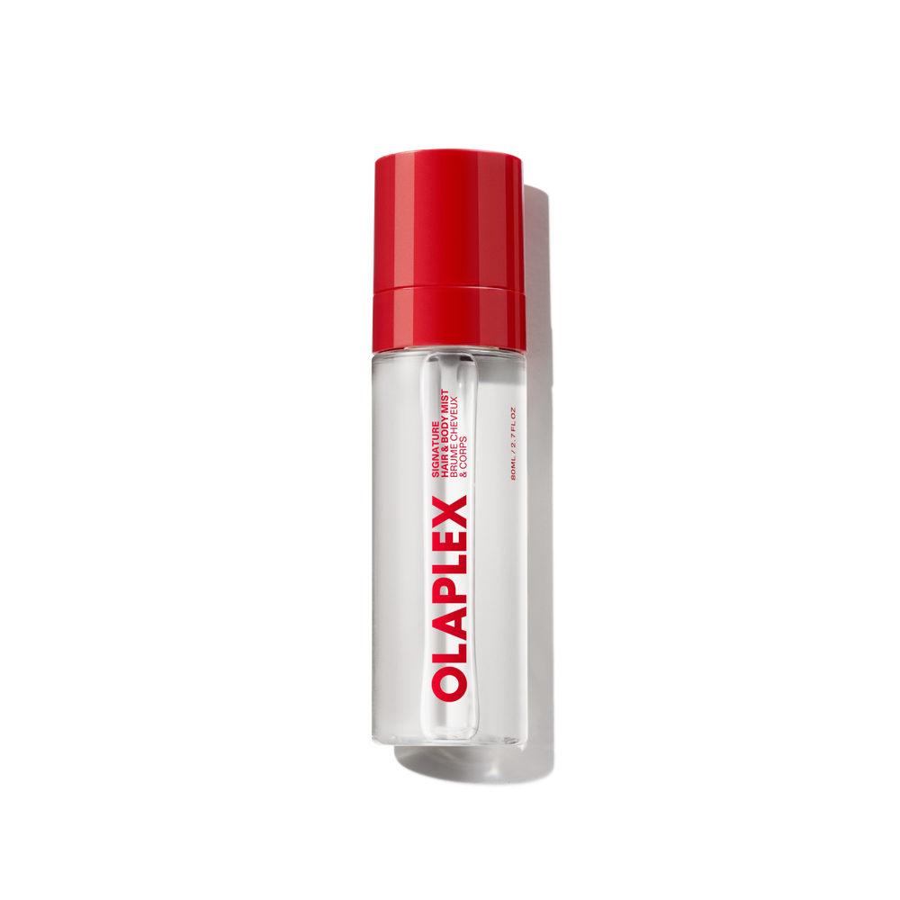 Un vaporisateur transparent de brume parfumée pour cheveux et corps Olaplex doté d'un bouchon rouge vif et du logo audacieux Olaplex imprimé verticalement sur le devant, présenté sur un fond de grille transparente. - main view