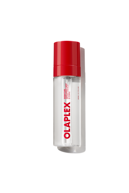Un vaporisateur transparent de brume parfumée pour cheveux et corps Olaplex doté d'un bouchon rouge vif et du logo audacieux Olaplex imprimé verticalement sur le devant, présenté sur un fond de grille transparente. - main view