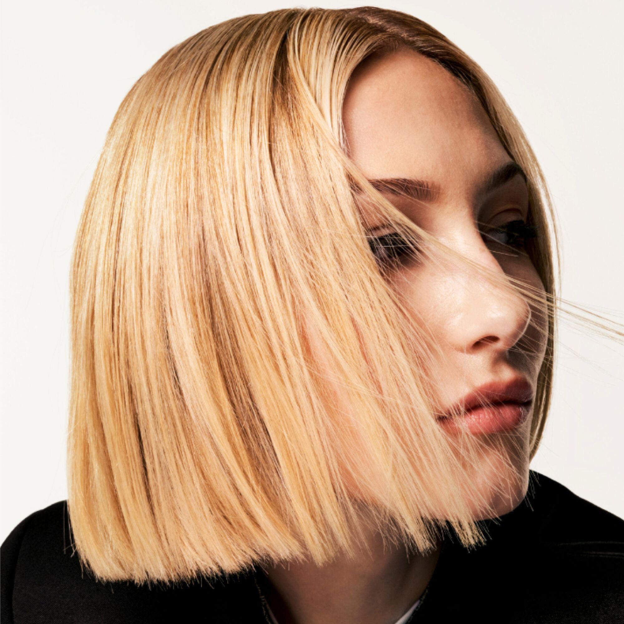 Woman with a stylish blonde bob haircut against a neutral background
