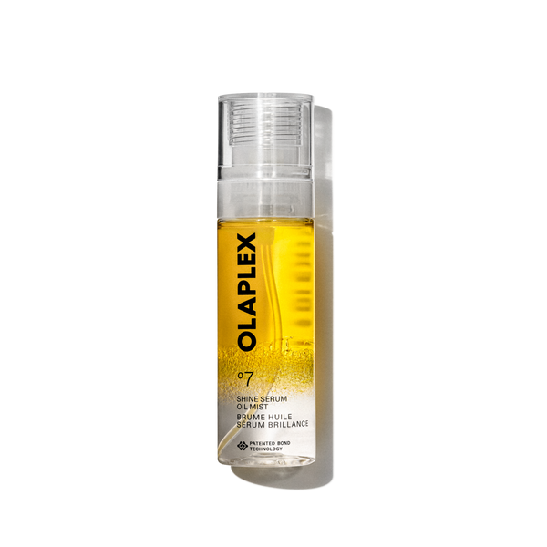 Photo du produit Olaplex No. 7 Shine Serum Oil Mist dans un flacon pulvérisateur transparent de 80 ml. La bouteille présente un liquide jaune vif visible à l'intérieur, un capuchon transparent et une étiquette blanche propre au bas avec un texte noir affichant le nom du produit, les détails et la signature "No. 7 " logo. La bouteille est isolée sur un fond quadrillé transparent. - main view